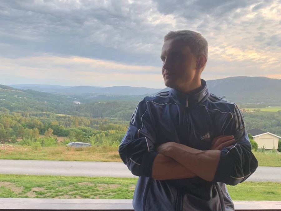 Stanislav on a balcony in Norway, hills behind him
